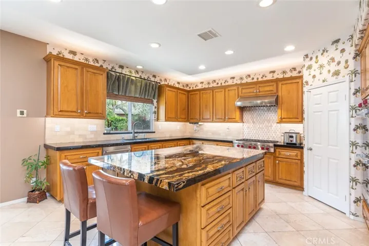 A warm and inviting kitchen featuring wood cabinetry and a granite island exudes culinary charm.