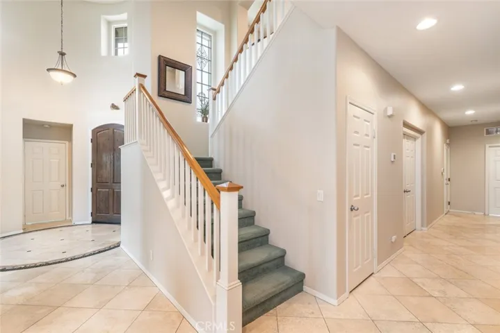 An elegant entryway with a sweeping staircase and natural stone flooring welcomes guests into a home of sophistication.