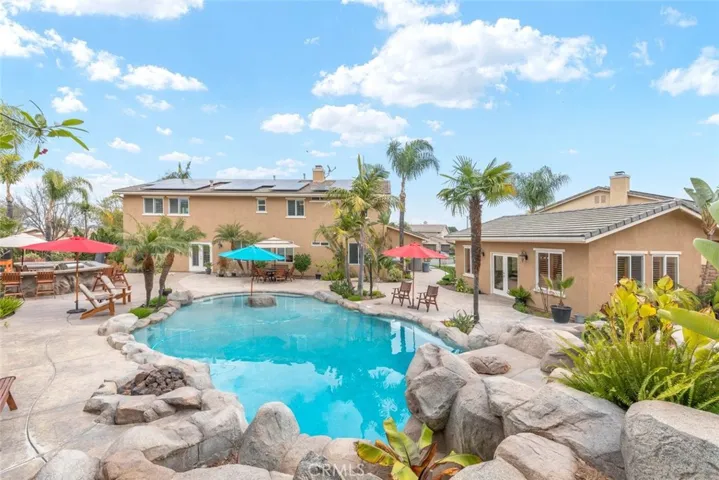 A charming pool house stands as a cozy haven, complemented by the surrounding vibrant greenery and the gentle ripple of the crystal-clear pool waters.