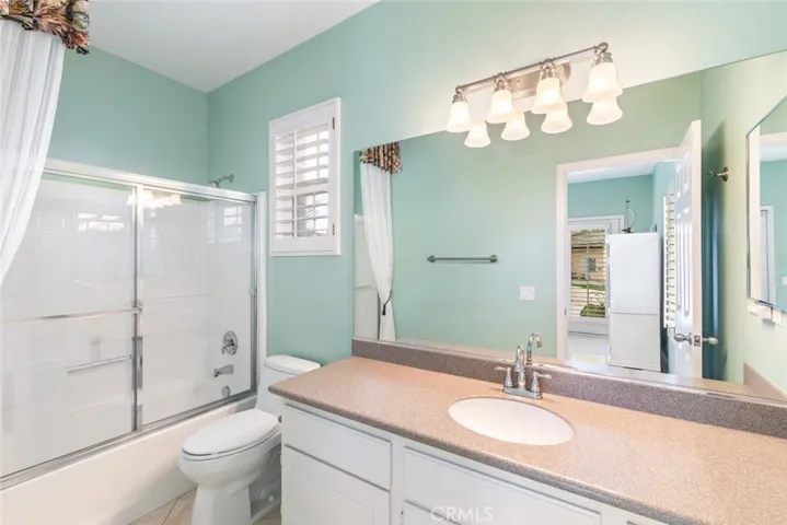 A pristine bathroom with a full-size shower and crisp white cabinetry reflects simplicity and function.