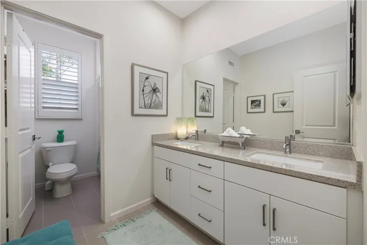 Guest bathroom with double sinks, quartz counter tops and tile flooring.