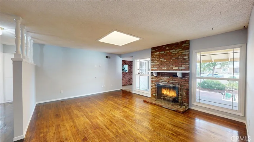 Living Room w/refinished wood flooring, skylight, freshly painted and upgraded dual pane windows.