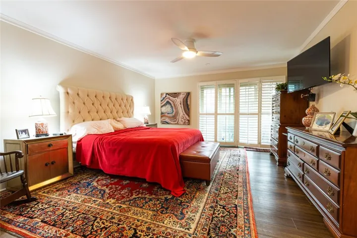 Master bedroom with plantation shutters leading to a private patio