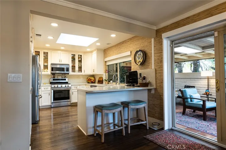 Gorgeous kitchen with quartz countertops, skylite, top of the line appliances and sliding door leading to the covered patio