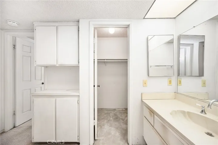 Standing in the shower over tub door viewing the large walk-in closet which extends to the right and also the left behind the linen cabinet.