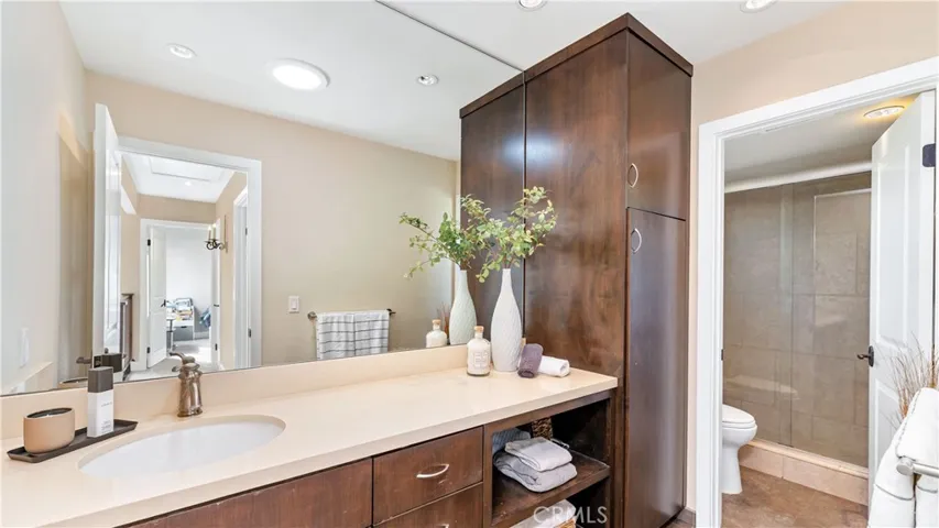 Upstairs hall bath features the same rich cabinetry as the primary Bathroom. There is plentiful counter space and storage cabinets and shelves. The walk-in tiled shower has its own door for privacy.