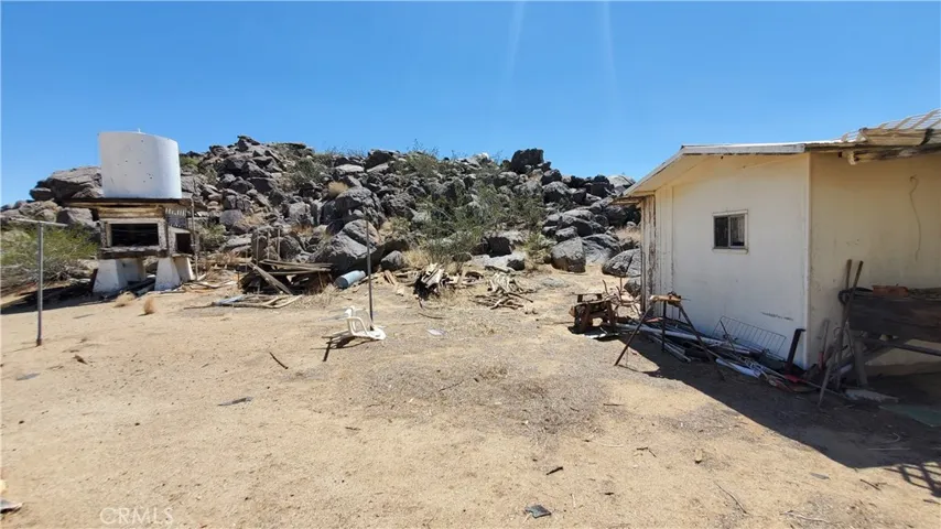 Pic across the backside of the detached bathroom looking at the rock outcrop. Old hauled water tank on the left.