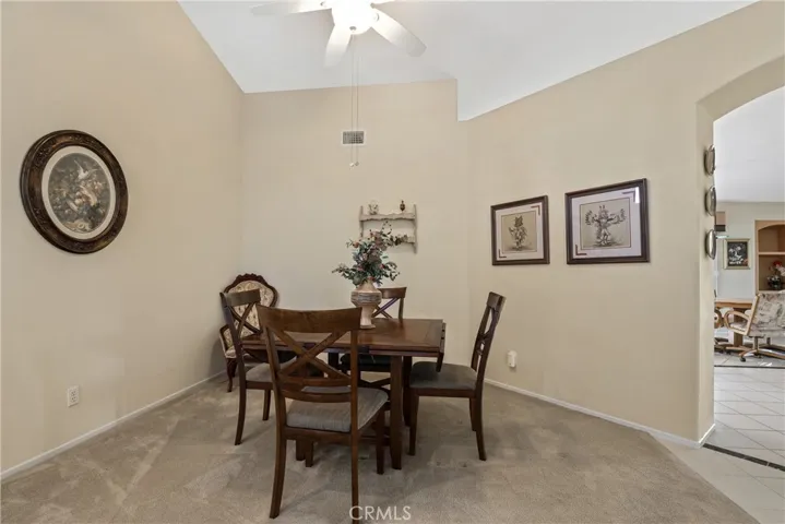 Formal dining room with vaulted ceiling and a fan.