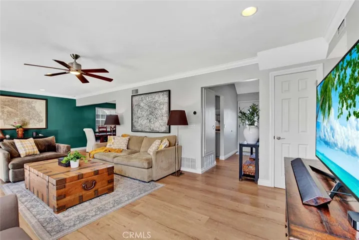 Entry Leads to this Very Large and Inviting Living Room with Wood Vinyl Flooring, Crown Molding, Recessed Lighting, Ceiling Fan, and Fireplace