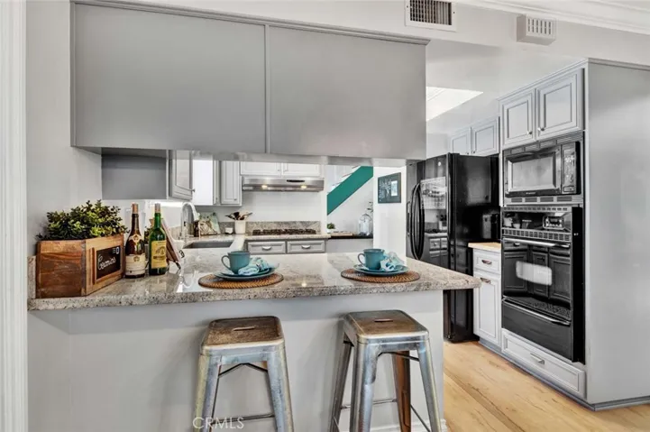 Kitchen has Granite Countertops, Stainless Sinks, a Garden Window, 5-Burner Gas Cooktop, Vent/Hood, Oven, Microwave, Dishwasher, Breakfast Bar, and Repainted Chic Gray Cabinetry