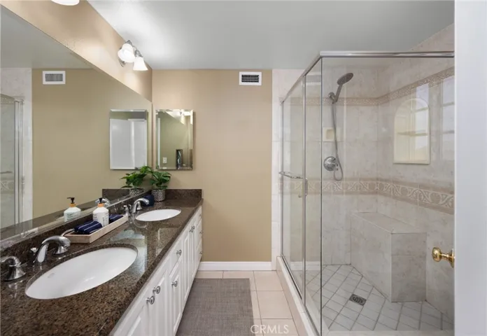Primary Suite with remodeled bath offering dual sinks and large shower with bench seating and seamless glass enclosure~