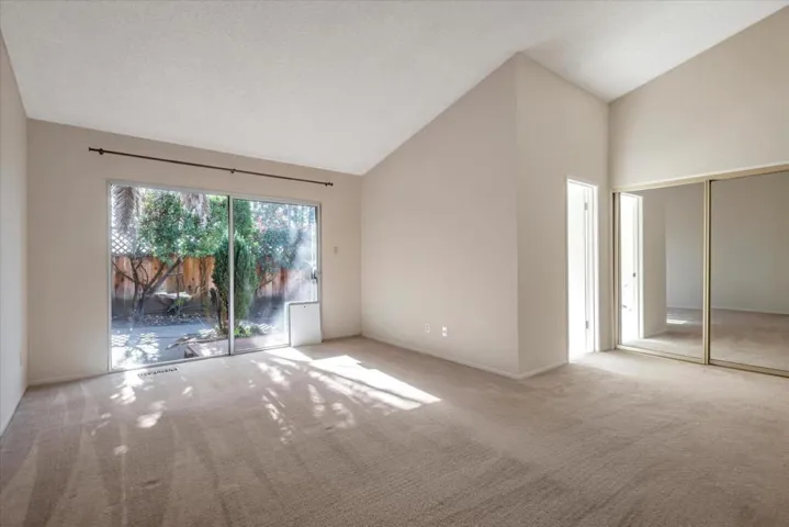 A comfortable size primary bedroom with dramatic ceiling and large closet