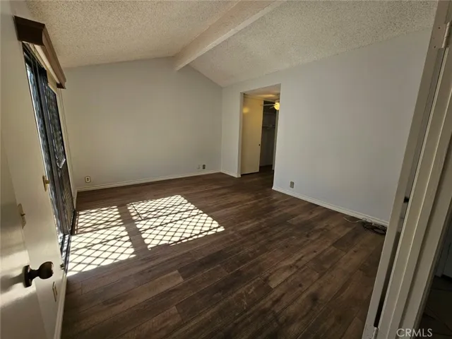Primary large bedroom features plank flooring, sliding door leads into the interior atrium, vaulted ceilings