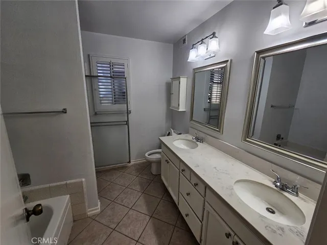 Primary bathroom features tile flooring, bath tub, walk in shower, double sinks