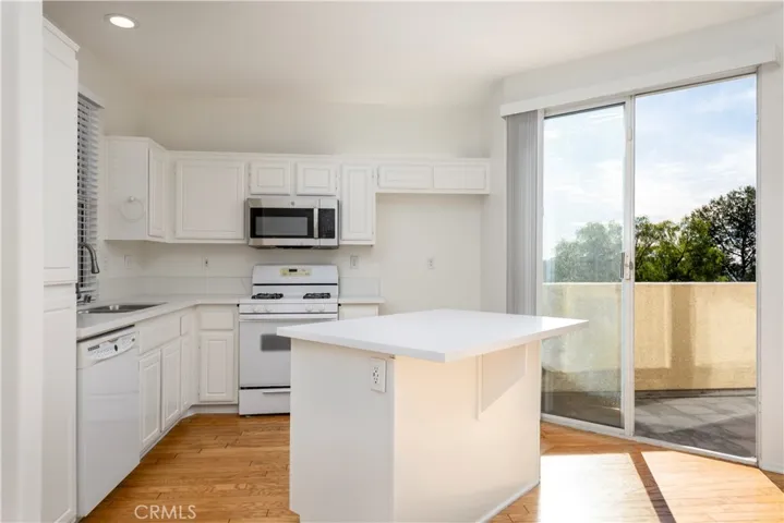 Kitchen has NEW Quartz Countertops, recessed lighting, dishwasher, stove and microwave, a slider that leads to patio space.