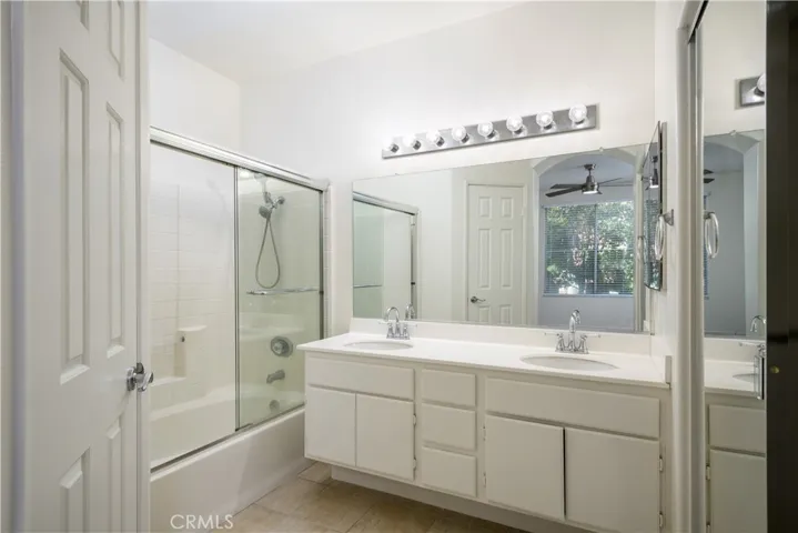 Primary En Suite with dual sinks, walk-in closet with mirrored closet doors, tub/shower combo, and privacy toilet closet.