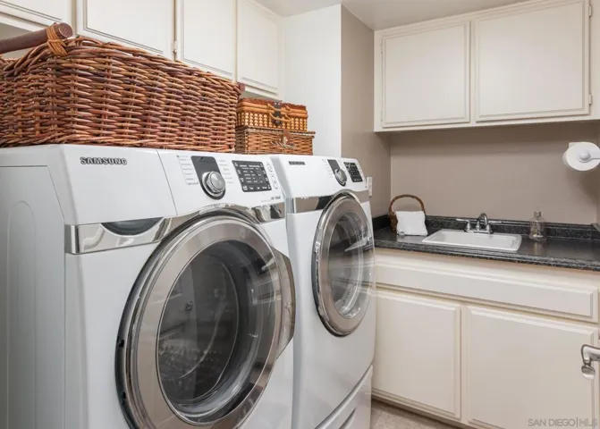Laundry has upper and lower cabinetry and sink.  Washer and Dryer convey.
