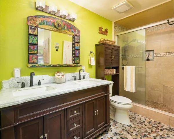 Shower has bench seat, stone surround to ceiling and handheld spray. Counter surface is Carrera marble.