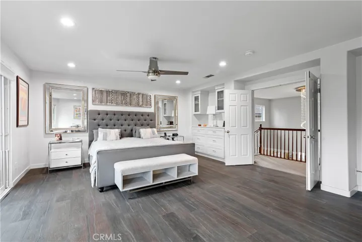Primary bedroom with hardwood flooring, double door entry, custom built-in, and remodeled recessed lighting!