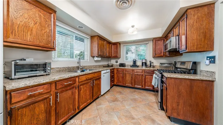 Granite Counters. Stainless steel sink. Kitchen overloos front yard.