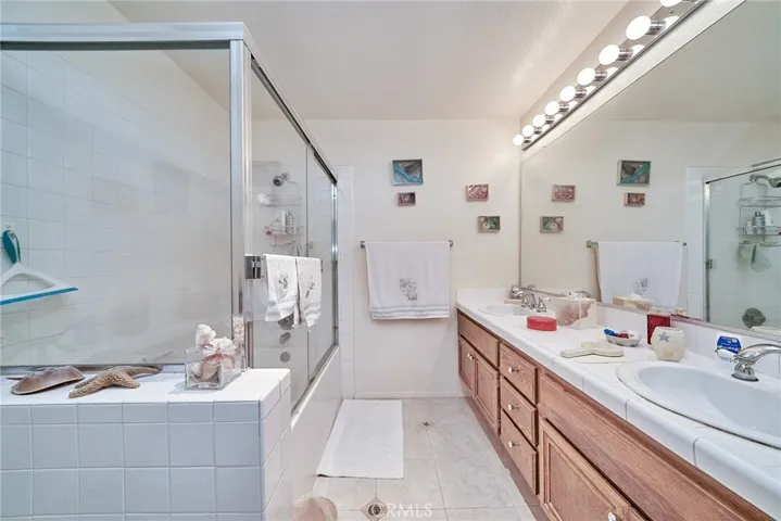 the master bathroom has a double vanity, tub/shower and custom tiling for this seaside condo.