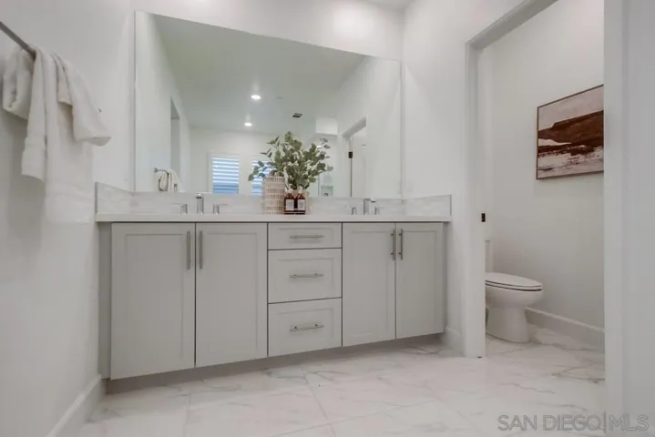 Enjoy a large primary bathroom with Denali white quartz counter, dual sinks, & Dama polished tile flooring.