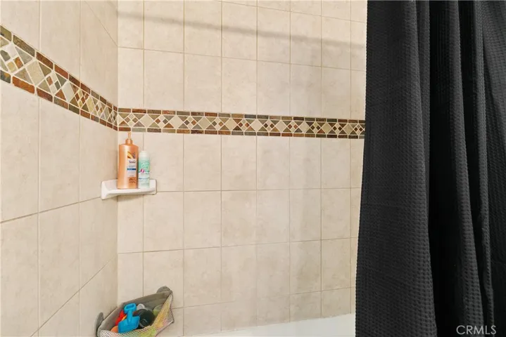 Tiled tub/shower in hallway bathroom.