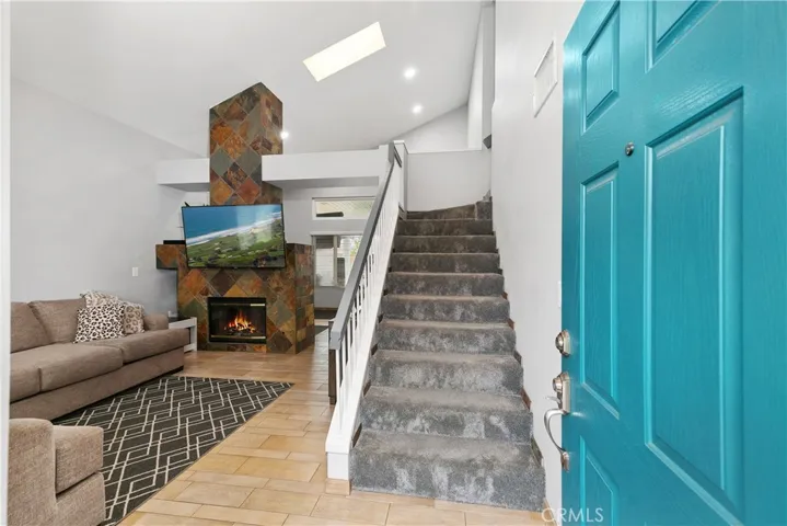 Entry into living room with tile flooring and carpeted stairs with dual sided fireplace.