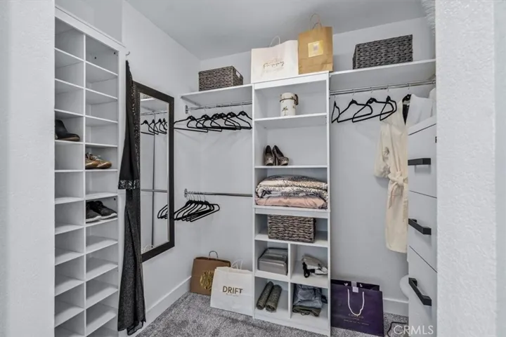 Primary suite walk in closet with built in organizers and drawers.