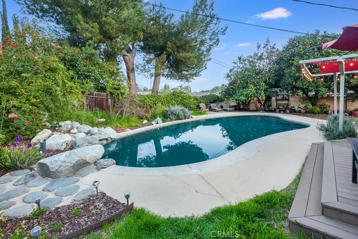 The private backyard will be a favorite entertainment destination with its sparkling in-ground pool with rock waterfall, low maintenance composite deck, sail covered pergola, special cool coating paint on the pool deck, low voltage lighting, lush green lawn, assorted fruit and citrus trees (pomegranate, fig, ruby red grapefruit, lemon, orange and Santa Rosa plum), and side yard with flagstone and relaxing fire pit.