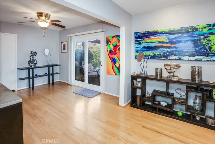 The family room that is bathed in natural light and is enhanced by recessed adjustable lighting, floating concrete shelving, a white brick fireplace with crushed glass, concrete mantle, rich oak hardwood floors and sliding glass doors that lead to the backyard.