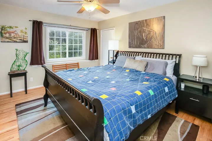 The primary suite is drenched in natural light and is further enhanced by a lighted ceiling fan, built-in media niche, expansive walk-in closet with organizers and gleaming oak hardwood floors.