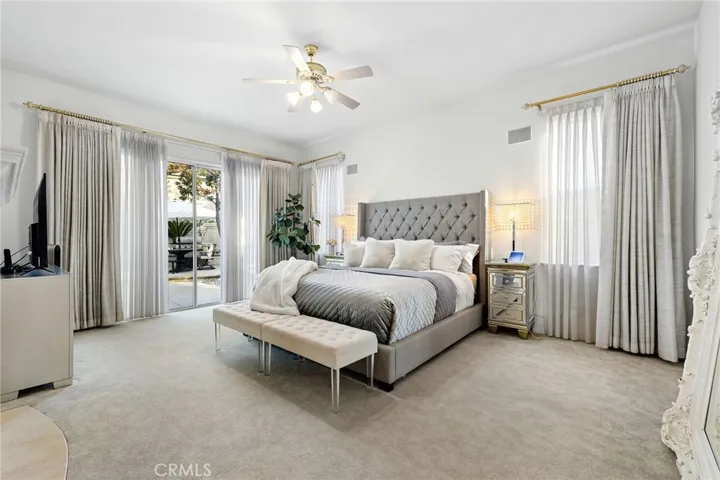 Primary bedroom with ceiling fan, drapes, and access to the backyard.