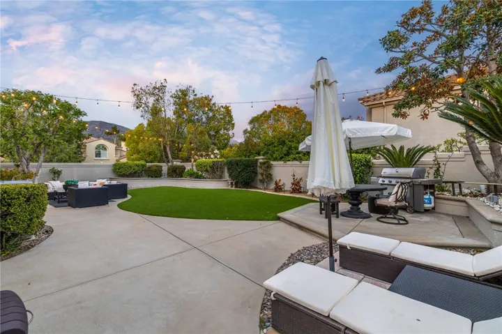 Backyard wit concrete decking, new artificial turf, and perimeter planters.