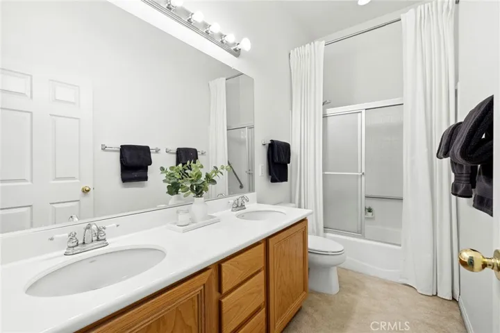 Hall bathroom offering dual sinks and a sliding glass shower/tub enclosure.
