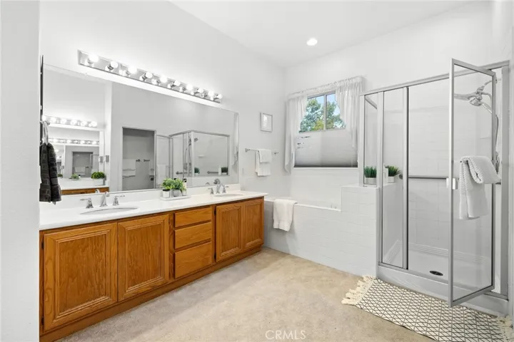 Primary bathroom offering dual sinks, a tub, and a walk-in shower with a glass enclosure.