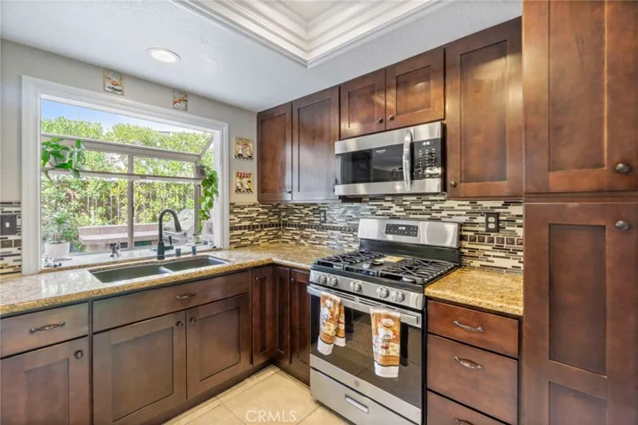 Remodeled kitchen with garden window, stainless steel appliances, granite countertops and tile backsplash.