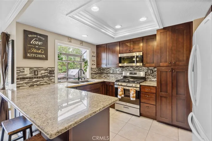 Remodeled kitchen with Granite countertops, tile backsplash, stainless steel appliances, casual eating sit at peninsula and garden window.