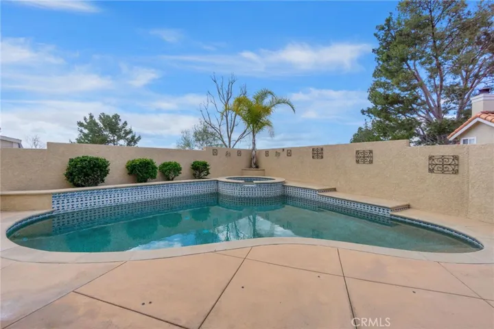 Private pool and spa with blue and white tile border. Private stucco/block walls.