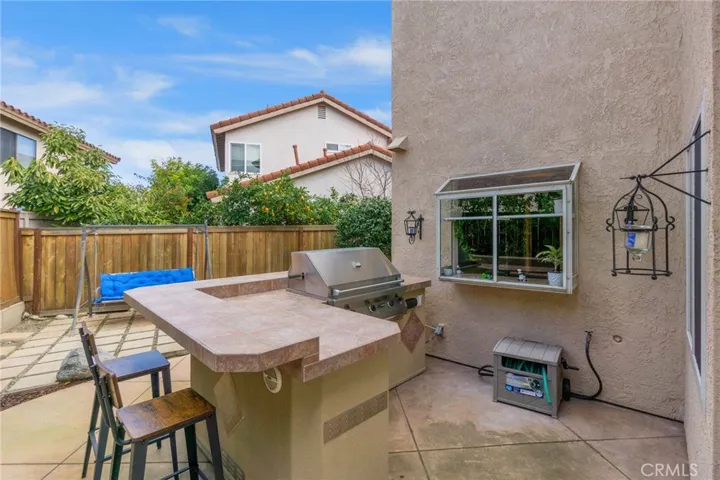 Built in BBQ with counter-top seating area. Kitchen garden window overlooks outdoor kitchen.