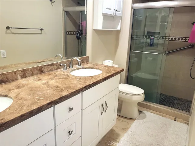 Primary suite vanity area with tile flooring and walk-in shower stall.