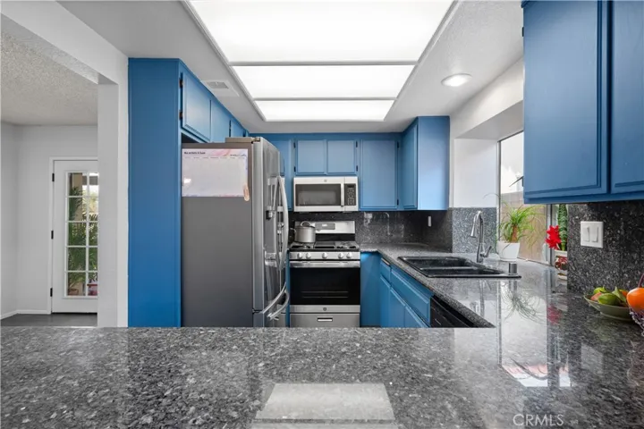 Kitchen bar flows seamlessly with gray stone granite tops