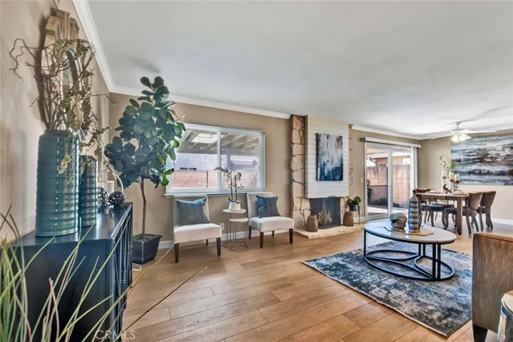 Elegant Living Room with Stone Fireplace, Crown Molding, wood Vinyl Flooring, and Adjacent Formal Dining Area