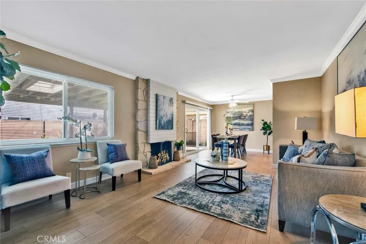 Living Room with Stone Fireplace, Crown Molding, wood Vinyl Flooring, and Adjacent Formal Dining Area