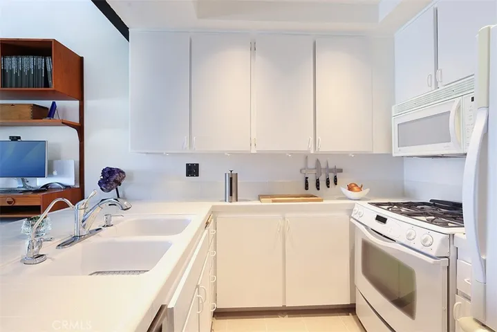 The pristine kitchen with dual sinks, beautiful cabinets, and Miele dishwasher.