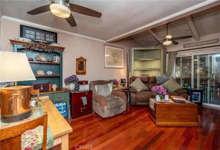 The living area has a space for dining and relaxing and entertaining and opens to the private balcony with a newer sliding door and features hardwood flooring and ceiling fans. Corner cabinet allows for additional storage.