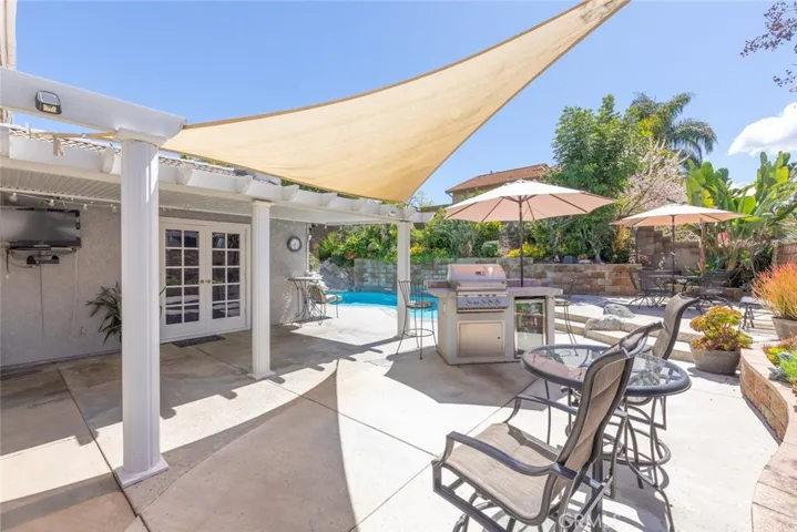 A sun-drenched patio with elegant shading offers a perfect spot for outdoor relaxation and entertainment by the pool.