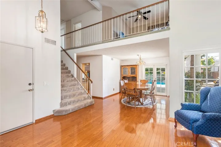 
Discover the warmth of this open-plan home with its inviting dining area, elegant staircase leading to an airy loft, and views to a serene poolside retreat.