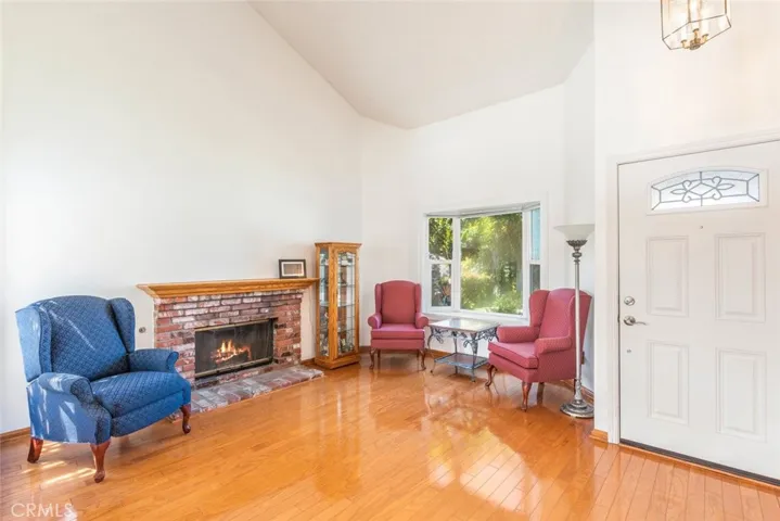 Step into a sunlit living space with gleaming hardwood floors, a cozy brick fireplace, that invite you to relax and feel at home.