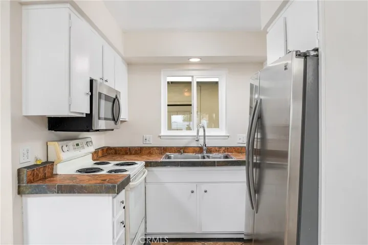 A nicely sized kitchen with white cabinetry and plenty of tile counter space